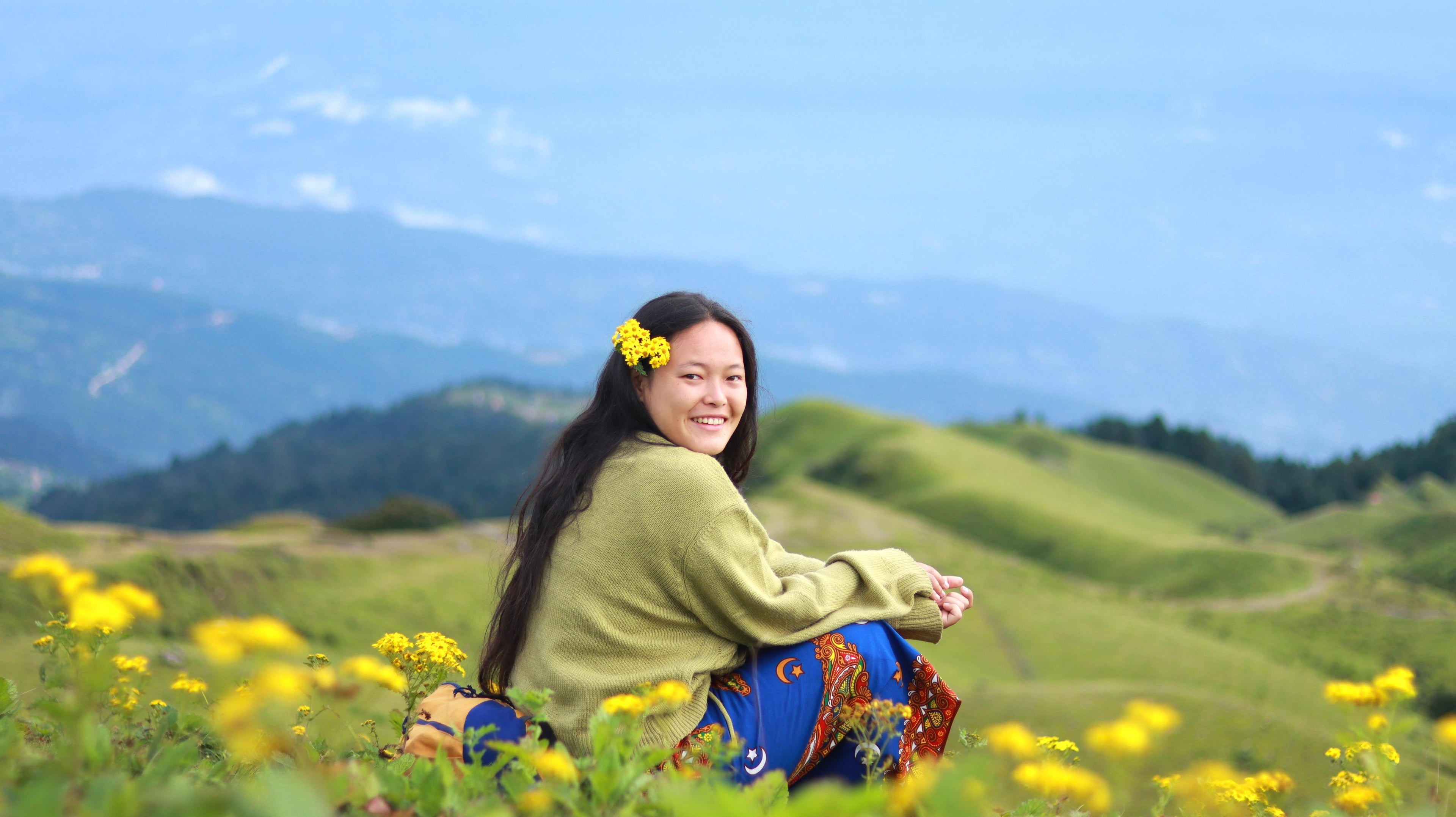 Oshin Angdembe posing in a traditional cultural dress amidst a flower-bloomed ground, showcasing the vibrant cultural heritage and natural beauty of Nepal.
