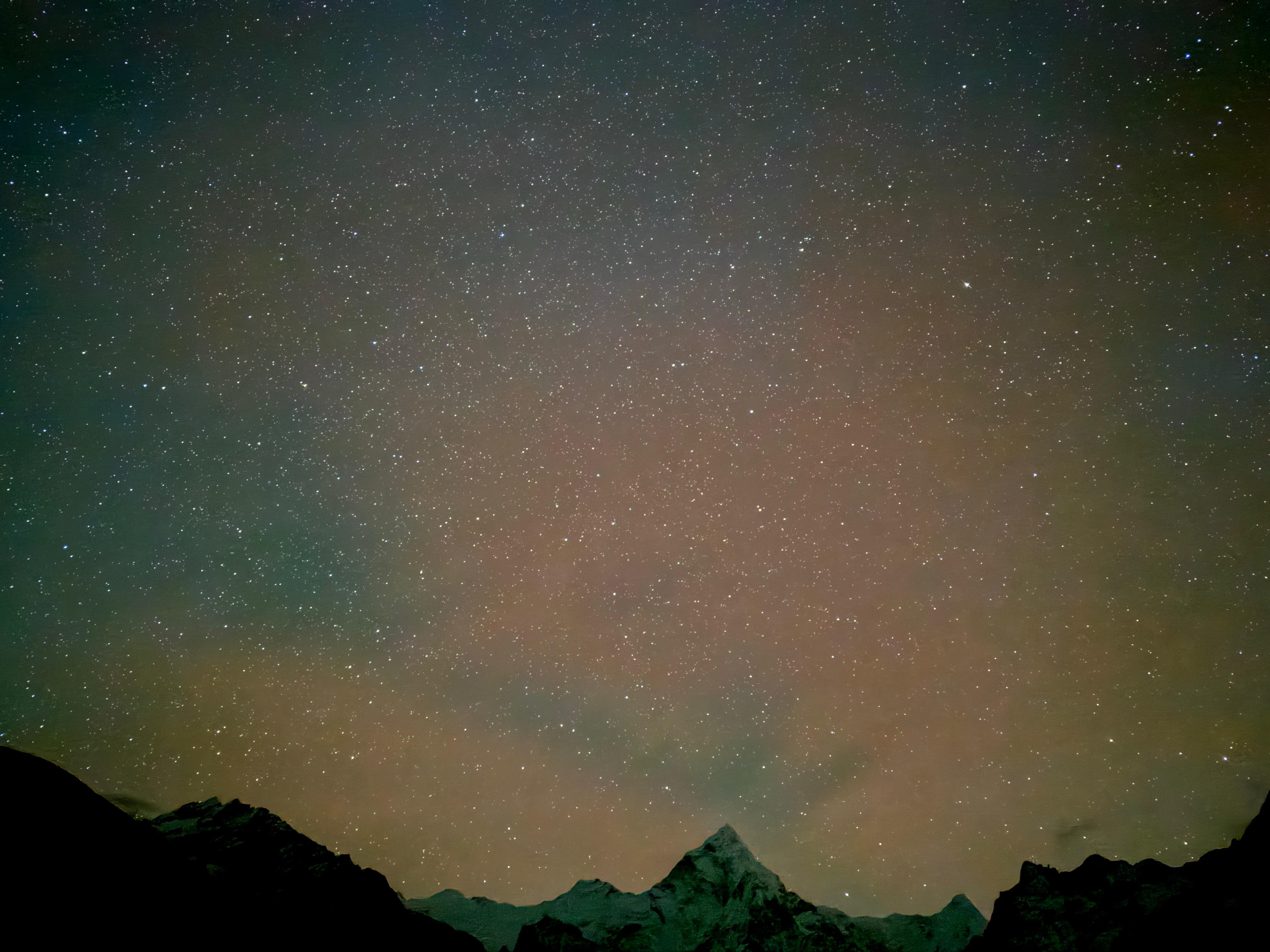 Night view of a mountain in the landscape, with the peak illuminated by the soft glow of moonlight, creating a peaceful and captivating atmosphere in the serene night sky.
